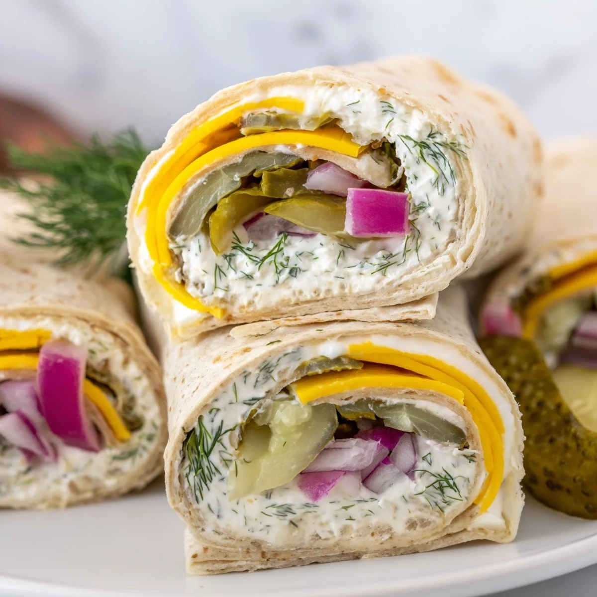 Tangy pickle-in-a-blanket snack garnished with fresh dill and creamy cheese layers.  