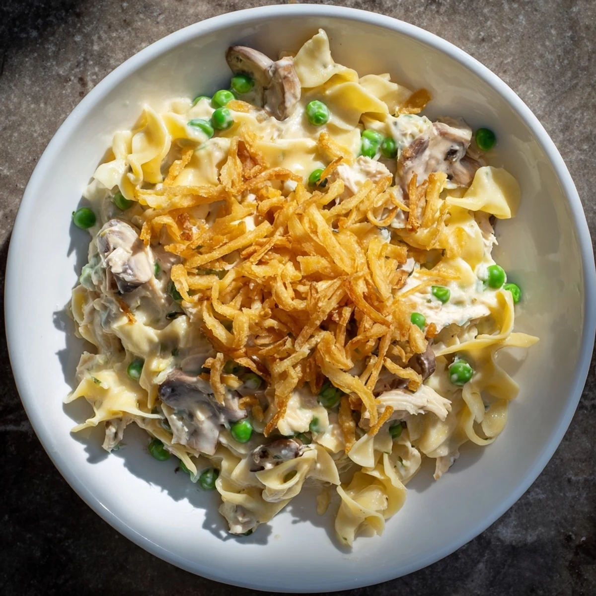 A close-up of creamy, bubbly homemade tuna noodle casserole with crispy onion topping, ready to serve.