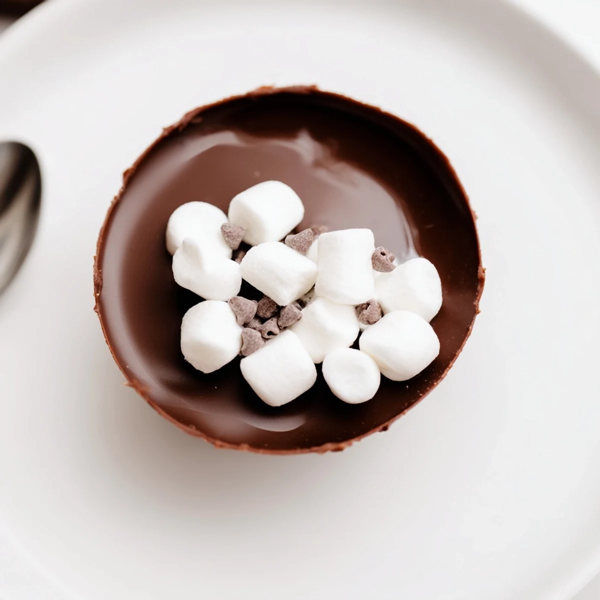 Homemade Budget-Friendly Hot Cocoa Bomb Cups, a swirl of melted chocolate with fluffy marshmallows.