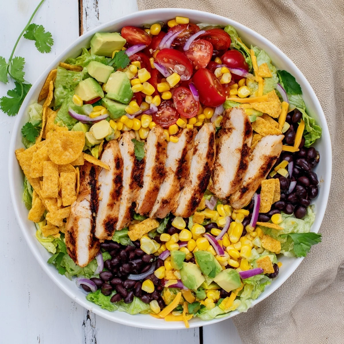 A vibrant Honey Lime Chicken Taco Salad with grilled chicken, romaine, corn, black beans, and avocado, served with tortilla strips.  