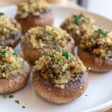 Close-up of baked Enchanted Forest Mushroom Nibbles, with herbs and cheese in their mushroom caps.