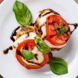 Fresh basil leaves garnish this easy one-skillet Caprese Chicken, served with a side salad for a vibrant Italian-inspired weeknight dinner.