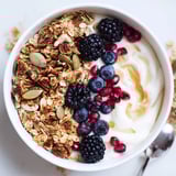 A close-up of a yogurt bowl with mixed berries and a cinnamon-ginger-nutty granola cluster, ready to enjoy.