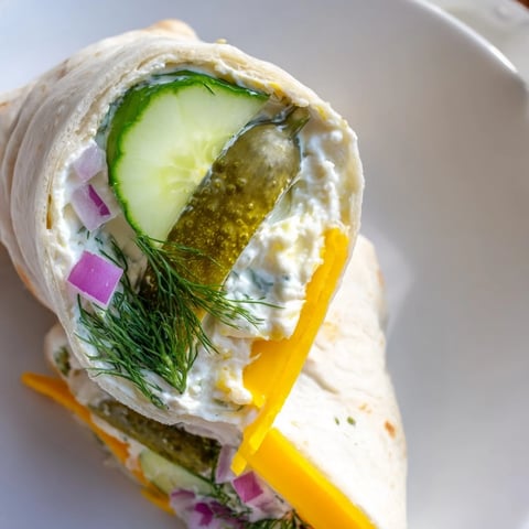 Crispy pickle-in-a-blanket rolls nestled in soft tortillas, bursting with cheesy flavor.  