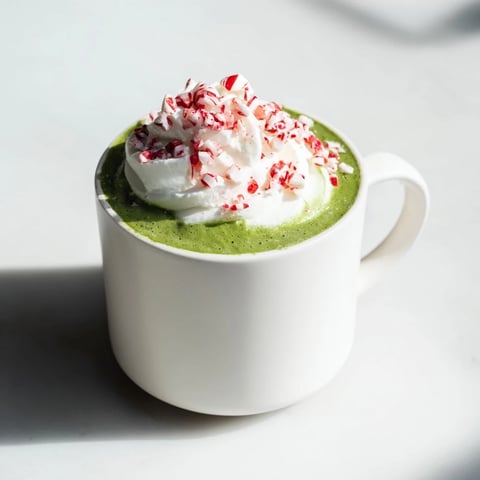 Cozy Peppermint Matcha Christmas Latte: A vibrant green drink topped with whipped cream and crushed peppermint.