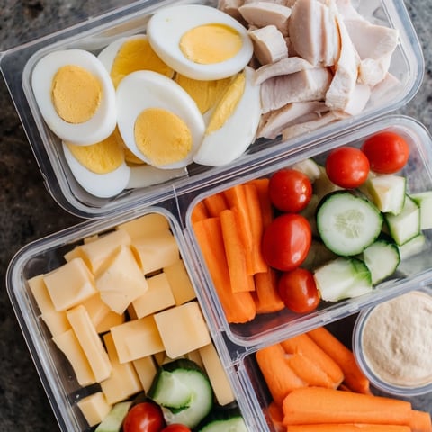 Protein snack boxes brimming with colorful veggies, lean meats, and creamy hummus for a healthy lunch.
