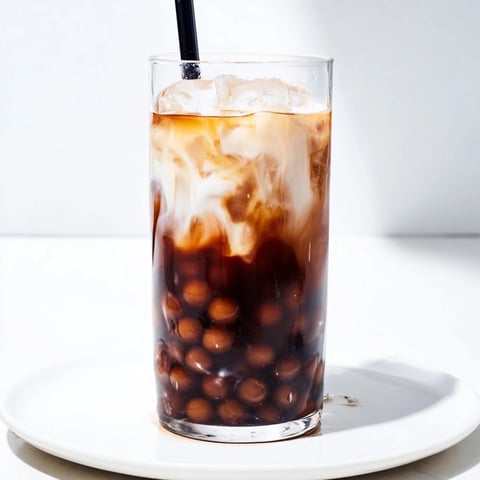 A tall glass filled with creamy Boba Tea Hack, swirling with tapioca pearls and ice.