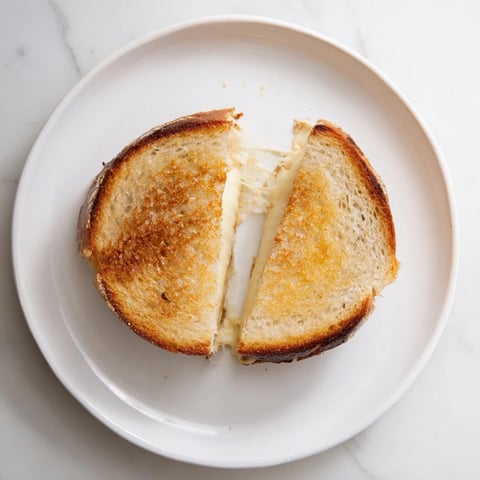 Golden-brown Three-Cheese Grilled Cheese with melted mozzarella, cheddar, and provolone oozing from crispy sourdough slices.  