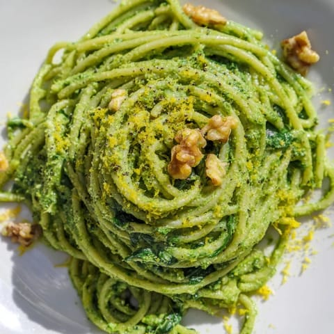 Fresh spinach and walnuts blend into a vibrant sauce for Creamy Spinach Walnut Pasta, garnished with lemon zest.  