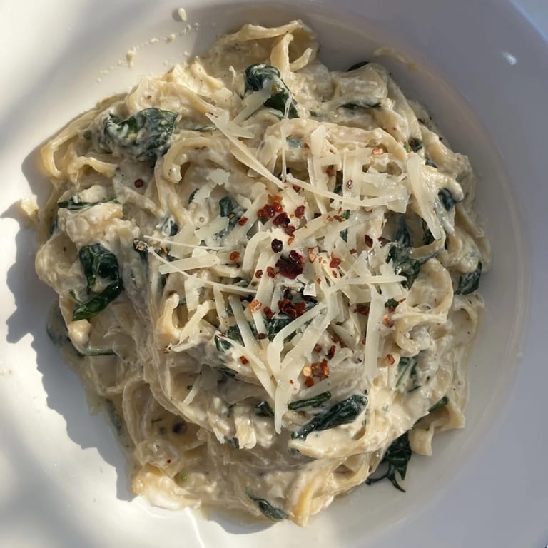 Deliciously light Lighter Fettuccine Alfredo with Spinach, garnished with parmesan and red pepper flakes.