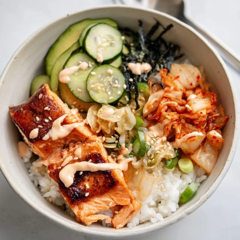 A delicious Crispy Salmon Rice Bowl served with cucumber and crispy garlic.  