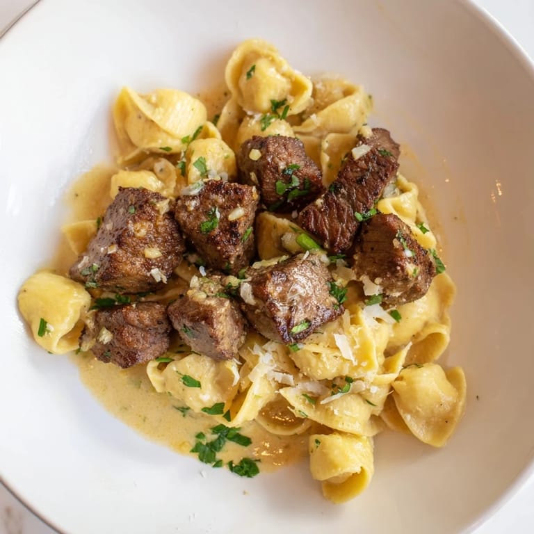 Close-up of succulent garlic butter steak bites, contrasting with the vibrant cheesy shells, ready to serve.