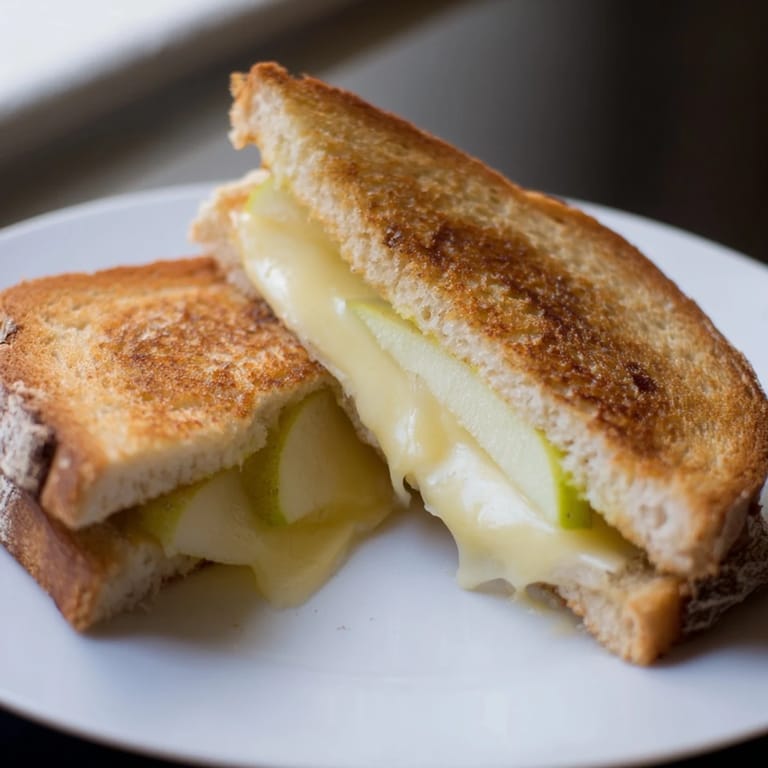 Warm Brie and Apple Grilled Cheese featuring gooey cheese and crisp apple, ready to slice and devour.