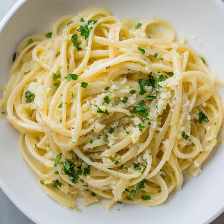 Creamy garlic butter linguine, a vegetarian delight, served hot with fresh Parmesan and lemon wedges.